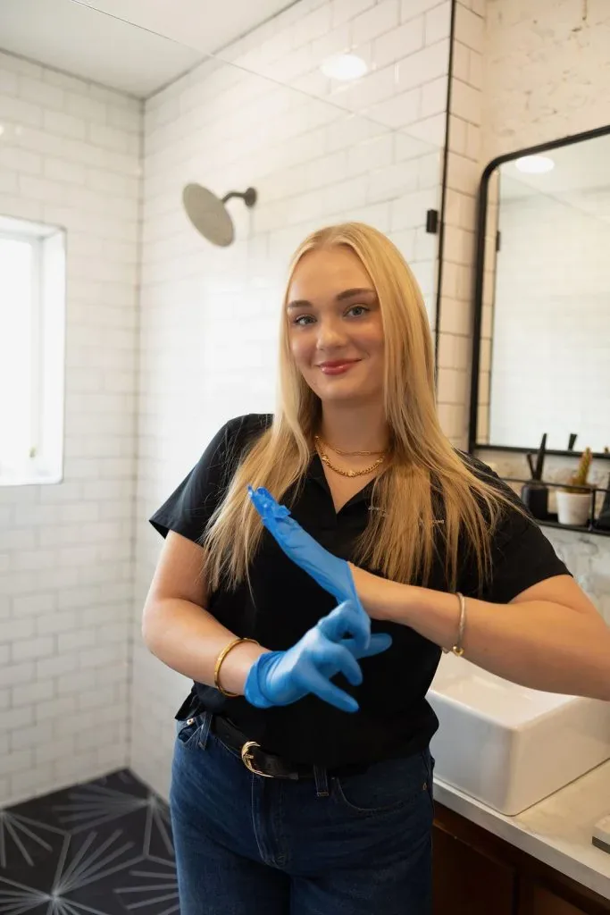 Maigan Dowell pulling on cleaning gloves in a client bathroom